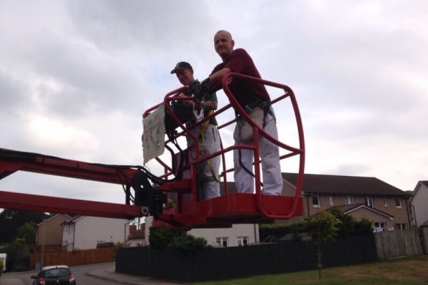 two workers standing on a cherry picker, ready to get to work