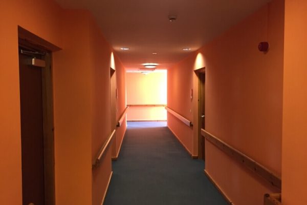 hallway painted orange, with wooden hand rails and doors