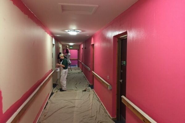 two men in the process of painting a hallway red